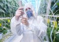 Waist up portrait of plantation worker wearing protective hazmat suit and mask in greenhouse of modern vegetable farm